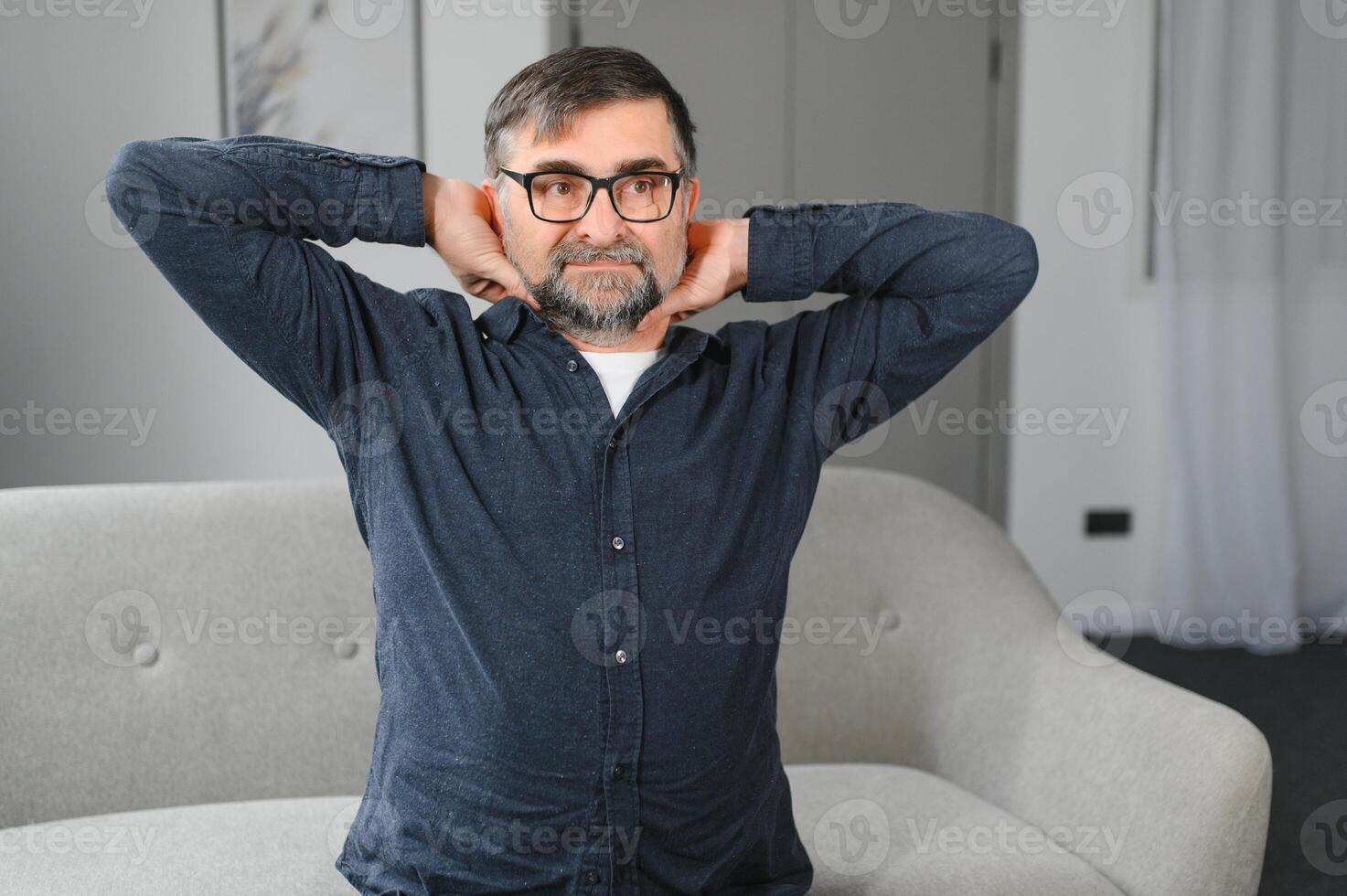 Old man has neck pain. Senior suffers from neckache indoor at home. photo