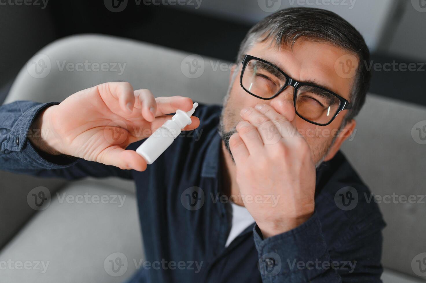 Illness And Sickness. Closeup Of man Feeling Sick Dripping Nasal Drops In Blocked Nose. Portrait male Sprays Cold And Sinus Medicine In Runny Nose. Sinusitis treatment photo
