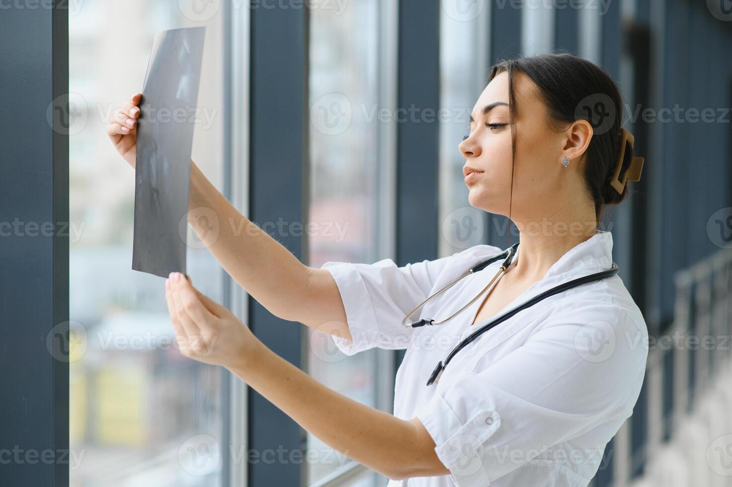 Young female doctor looking at the x-ray picture of lungs in hospital. photo