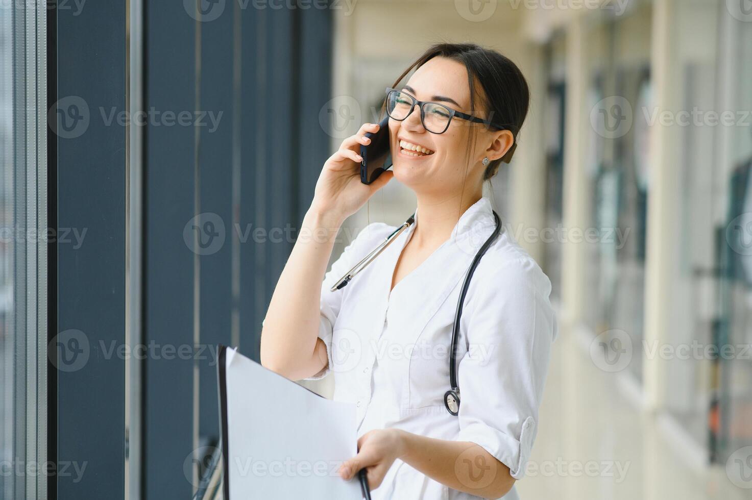 Female doctor talking by mobile phone in clinic photo