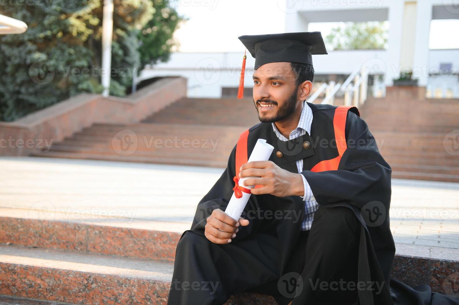 Handsome indian graduate in graduation glow with diploma. photo