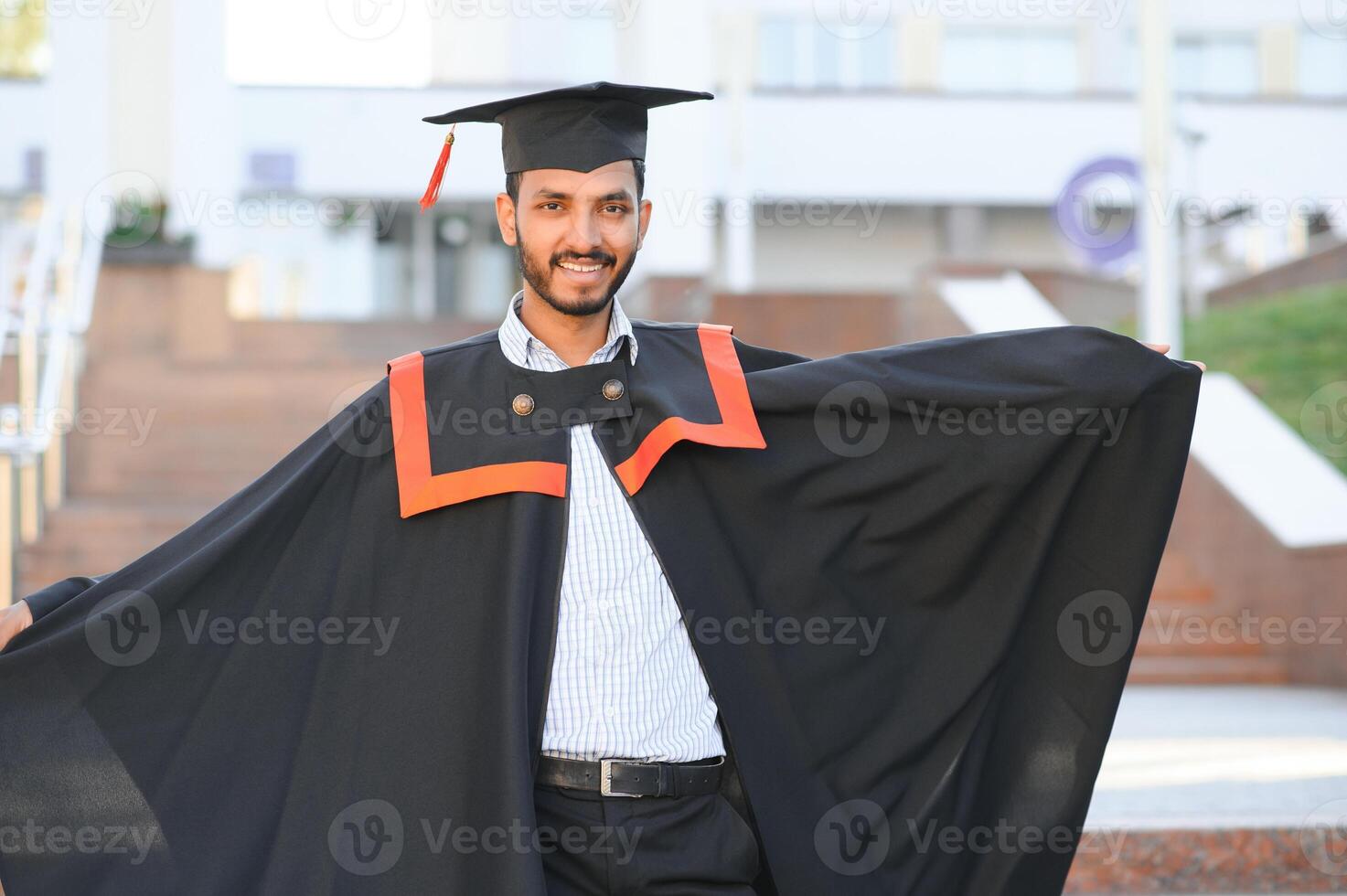 Portrait of indian handsome male graduate in graduation robe. photo