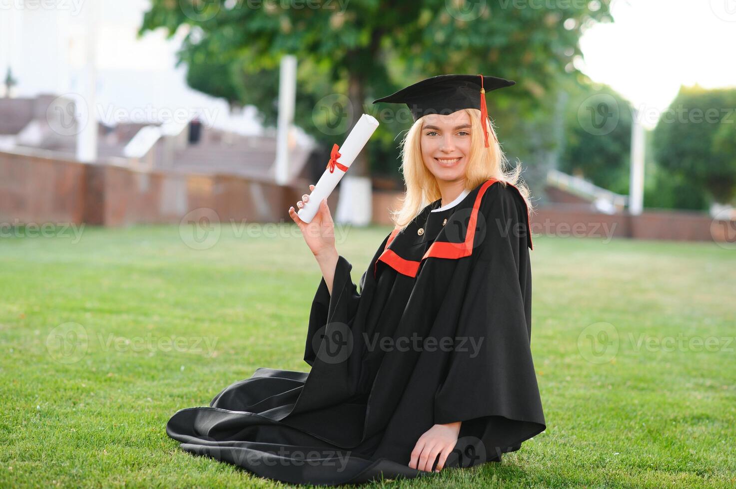 Portrait enthusiastic female college student graduate in cap and gown celebrating, holding diploma. photo