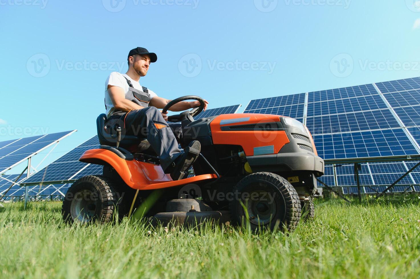 A man drives a lawnmower near solar panels. Concept of solar energy photo