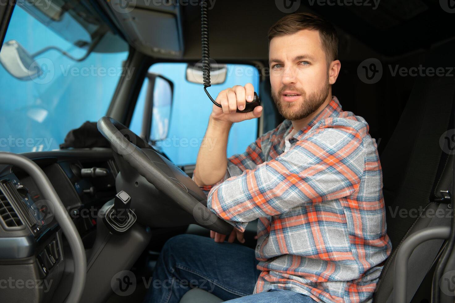 Male truck driver talking by CB radio system in his vehicle photo