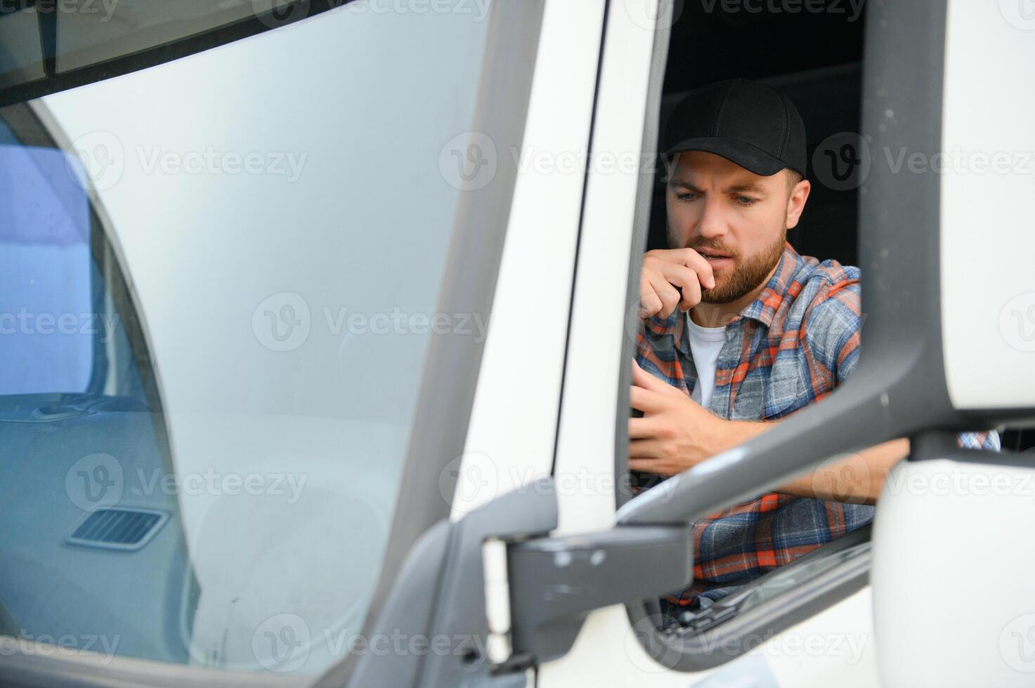 Man trucker driving in a cabin of his truck and talking on radio transmitter. photo