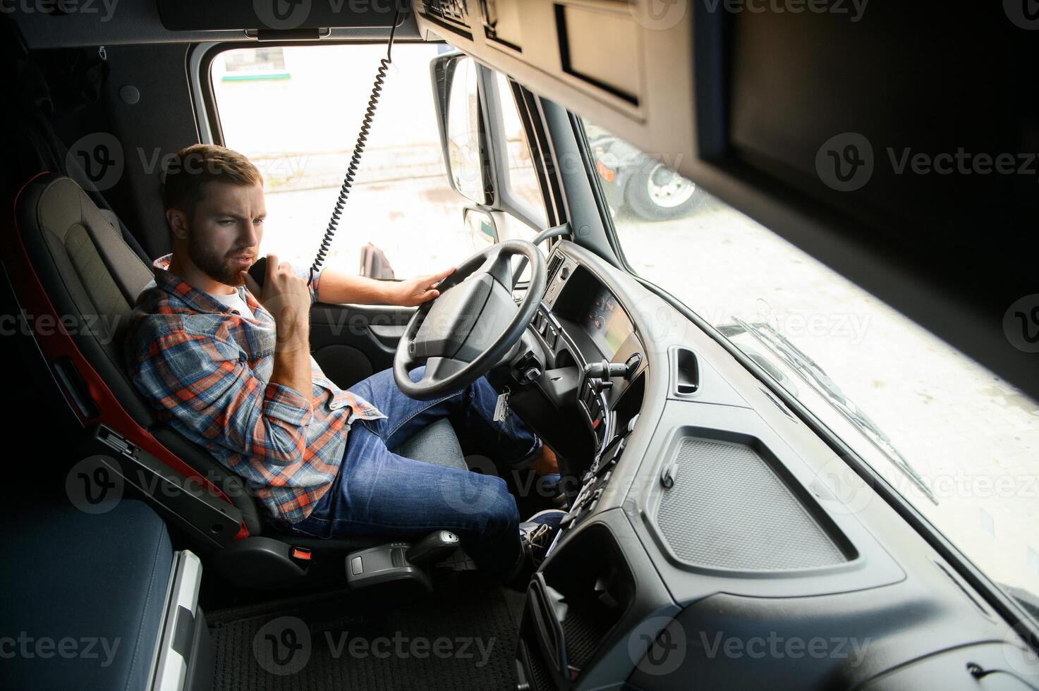 Man trucker driving in a cabin of his truck and talking on radio transmitter. photo