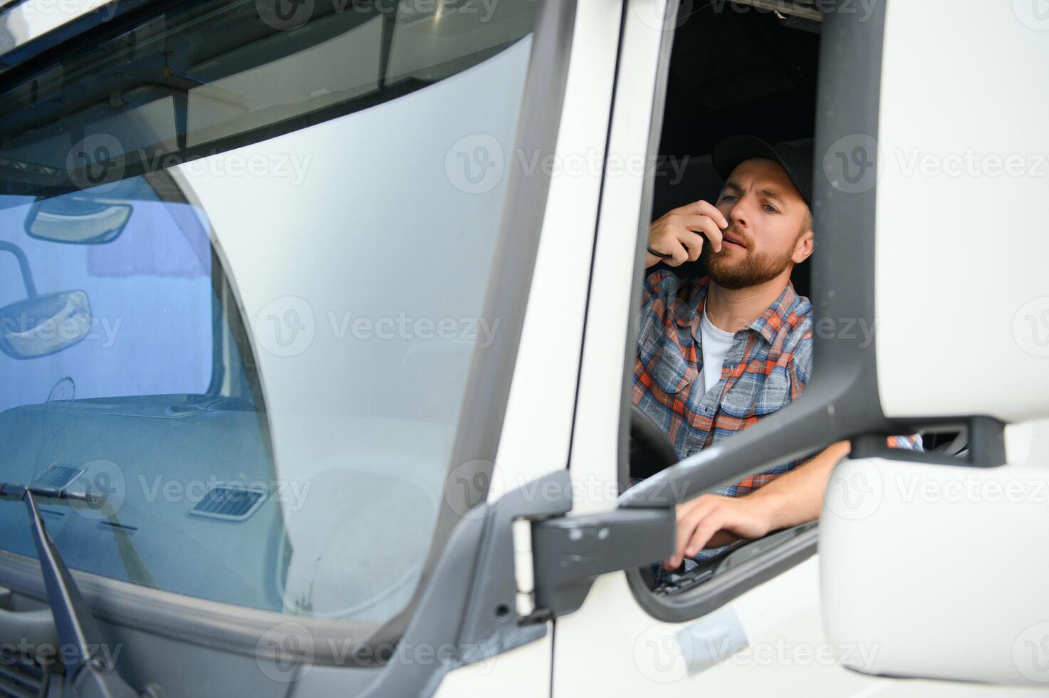 Man trucker driving in a cabin of his truck and talking on radio transmitter. photo