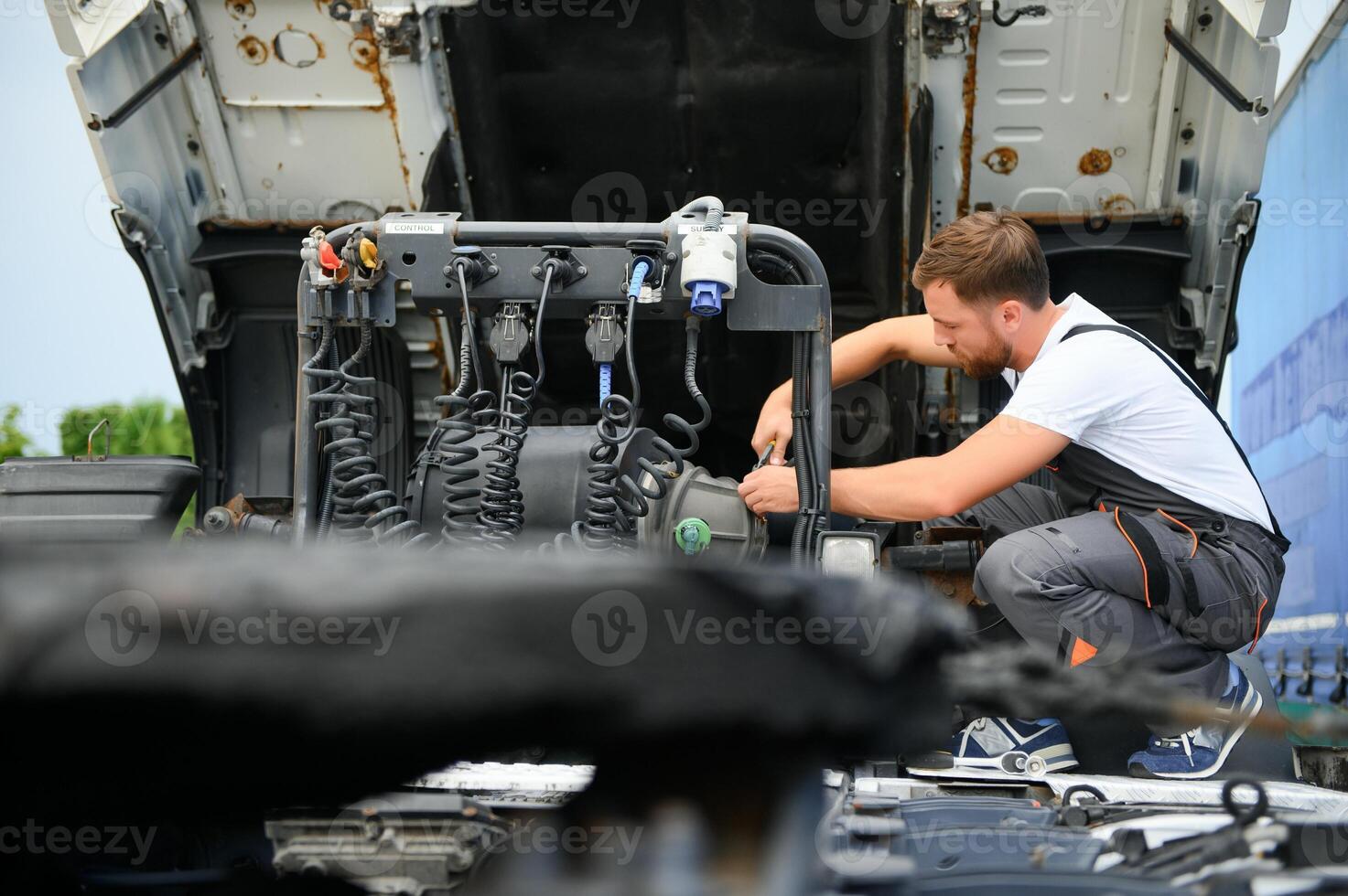 Semi Truck Maintenance. Caucasian Truck Service Worker in His 30s Performing Scheduled Recall Maintenance. photo
