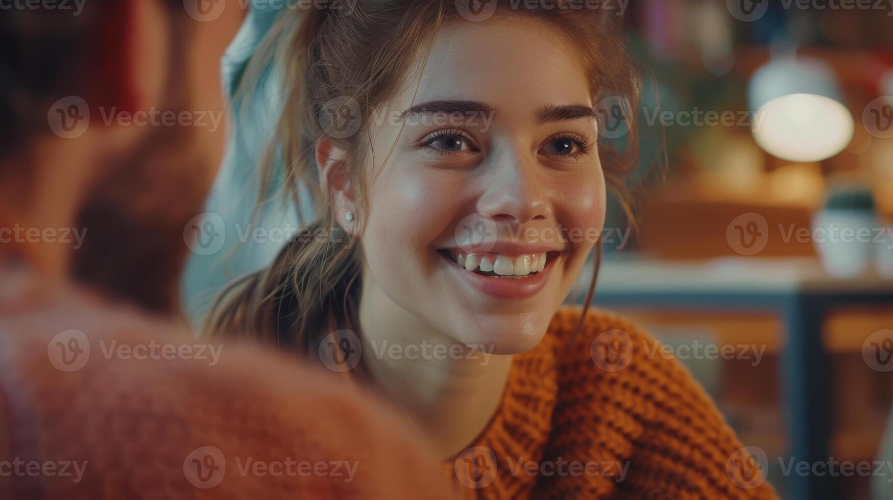 joven mujer sonriente a alguien en un café a noche foto