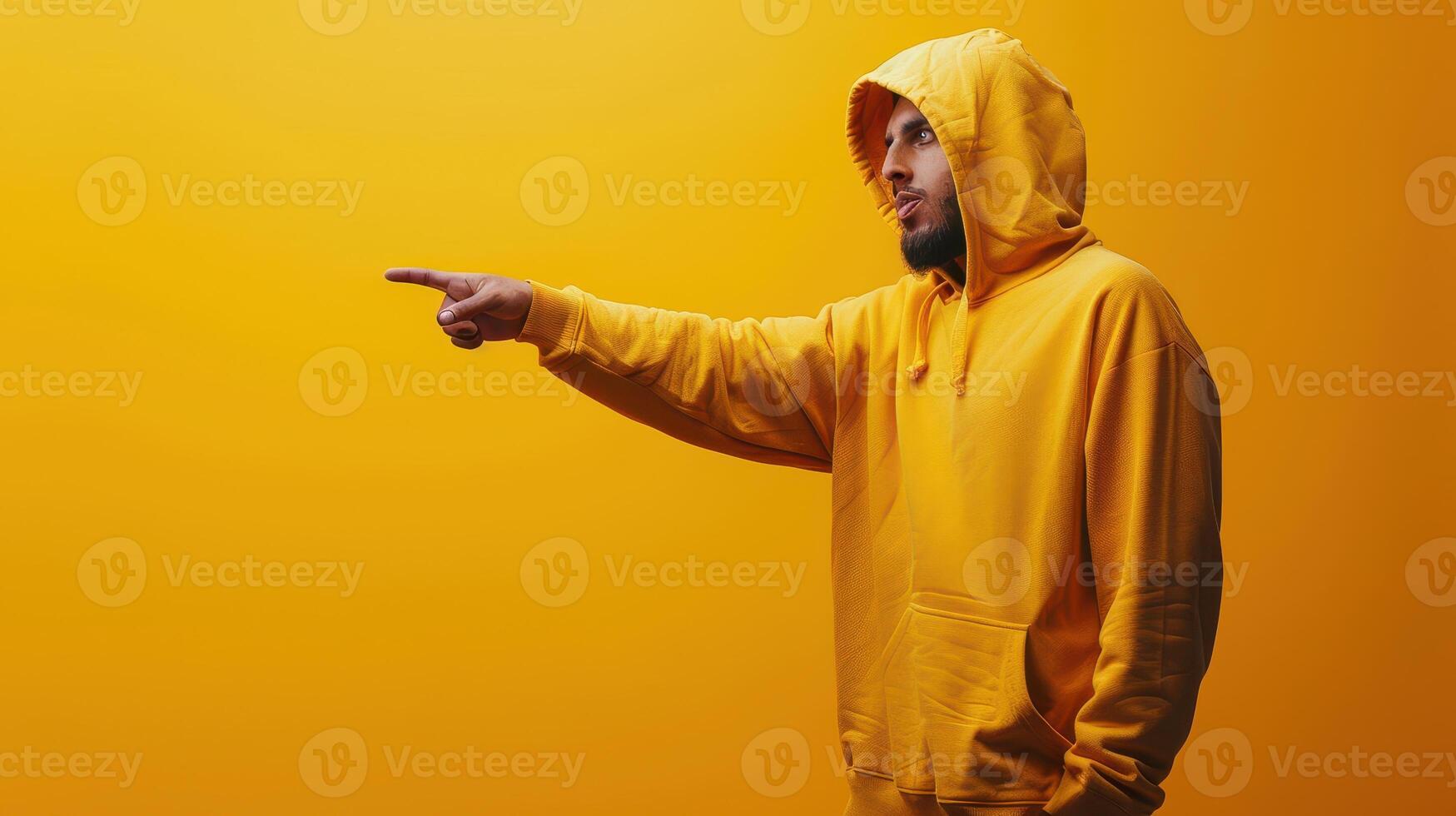 Man Wearing Yellow Hoodie Points to the Right in Front of a Yellow Background photo