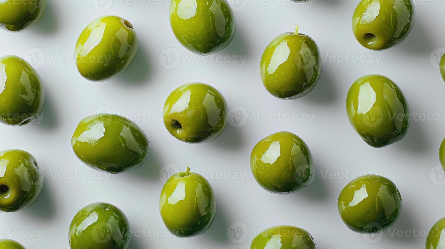 Green Olives Spread Across a White Background Highlighting Their Glossy Texture and Varied Shapes. photo