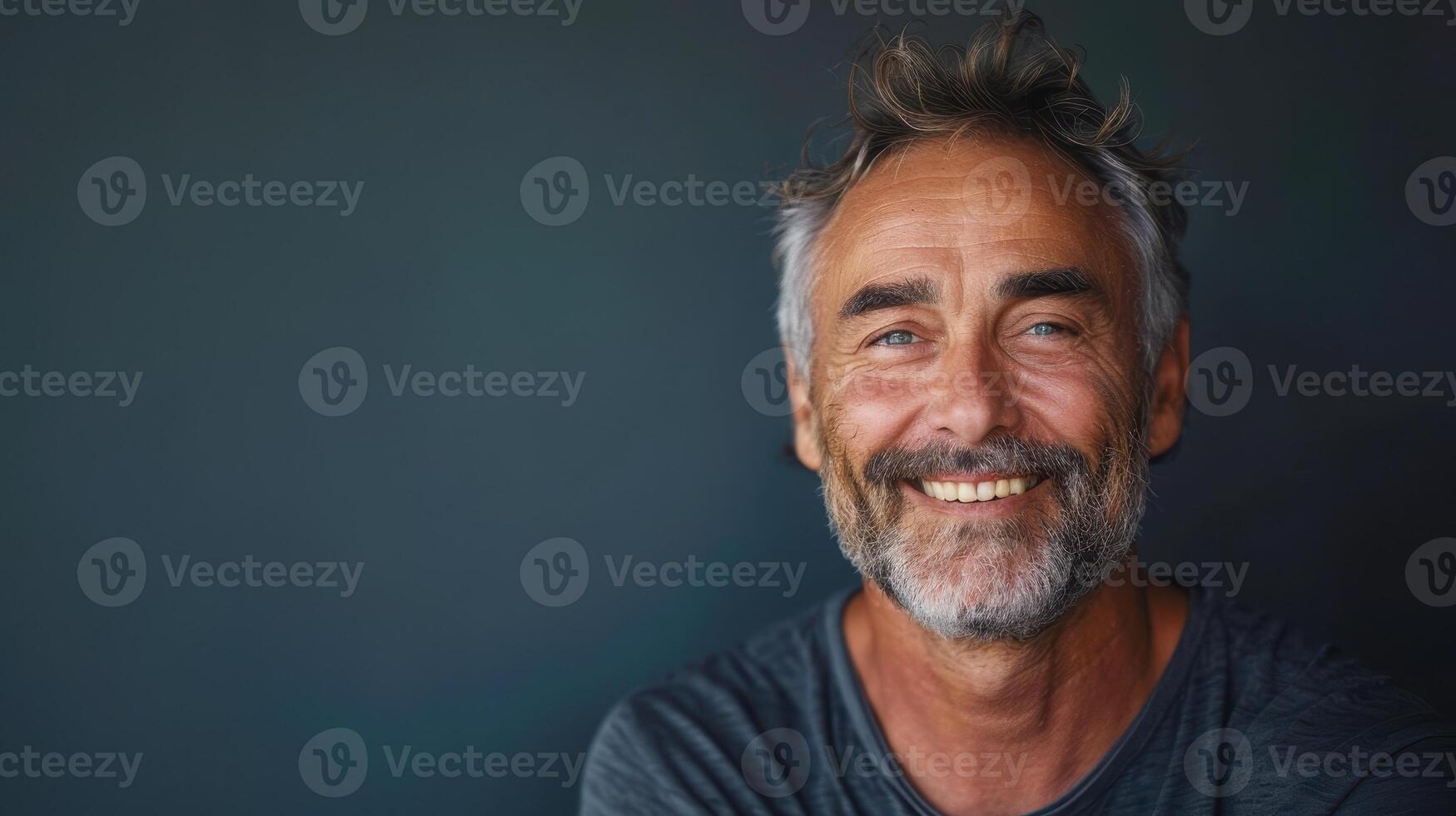 Joyful Older Man With Graying Beard Smiling in Relaxed Pose Against Dark Background photo