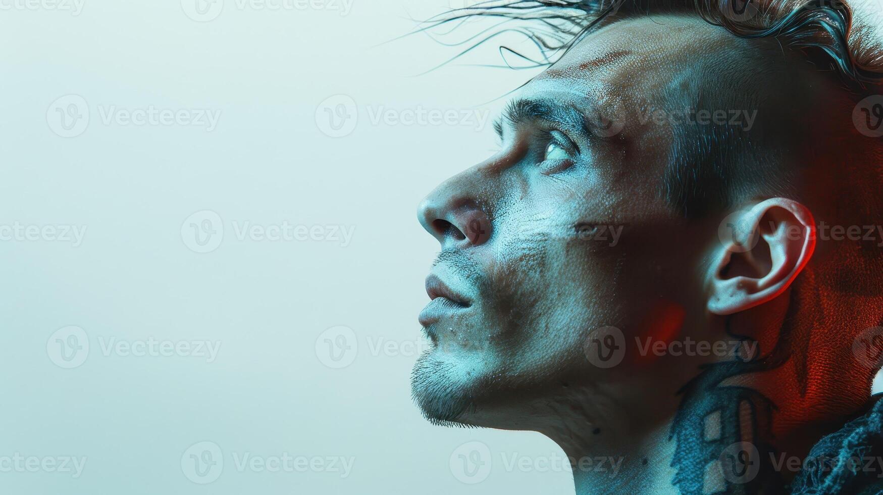 Intense Portrait of a Tattooed Man in Profile Bathed in Soft Blue and Red Light Against a Gradient Background photo