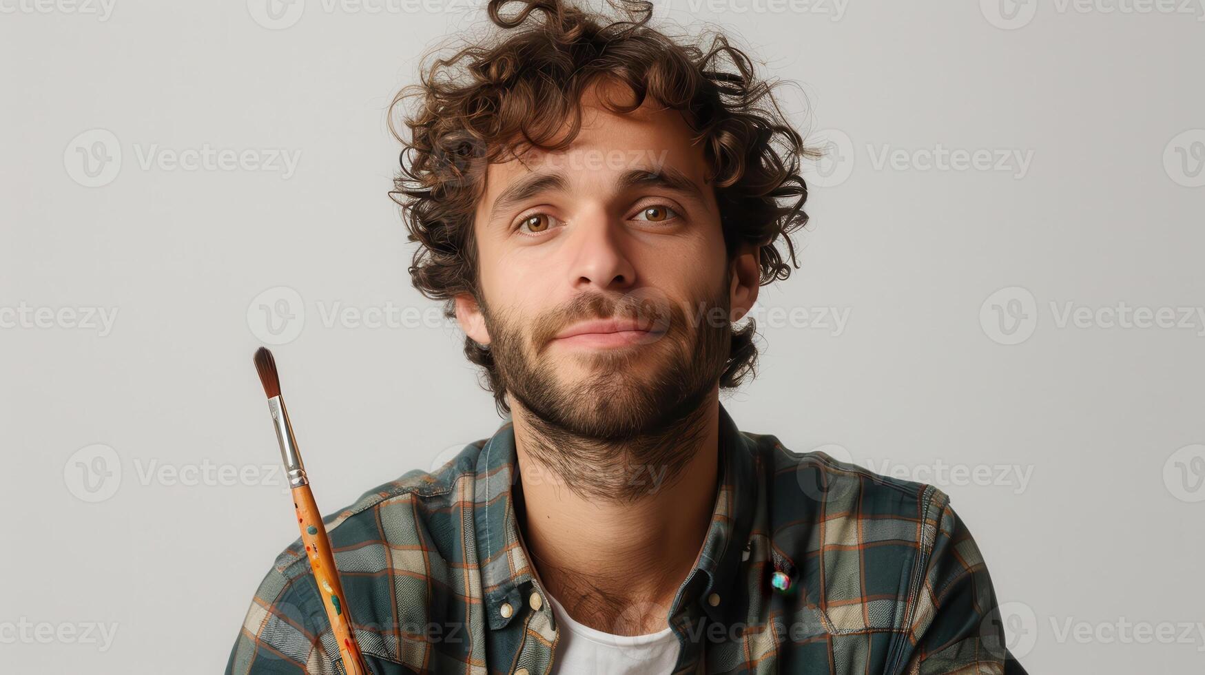 Artistic Expression of a Young Man Holding a Paintbrush in a Studio Setting During Daylight photo
