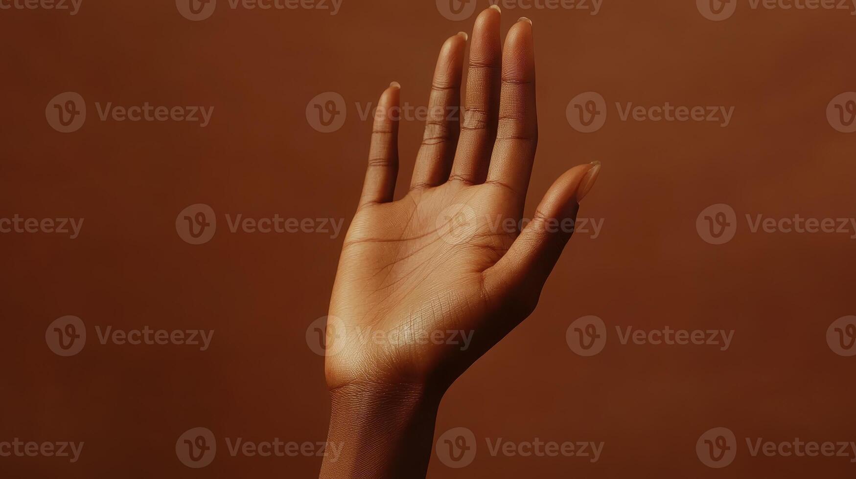 A Close-Up View of an Upward Reaching Hand Against a Warm Brown Background in Soft Natural Light photo