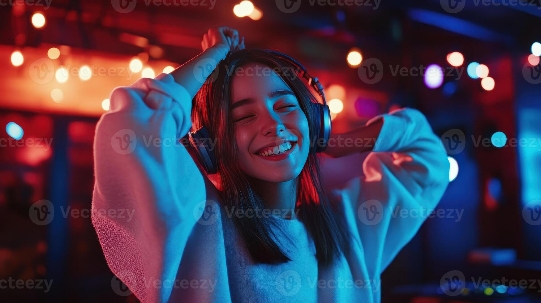 A young woman enjoys music while dancing in vibrant nightclub lighting photo