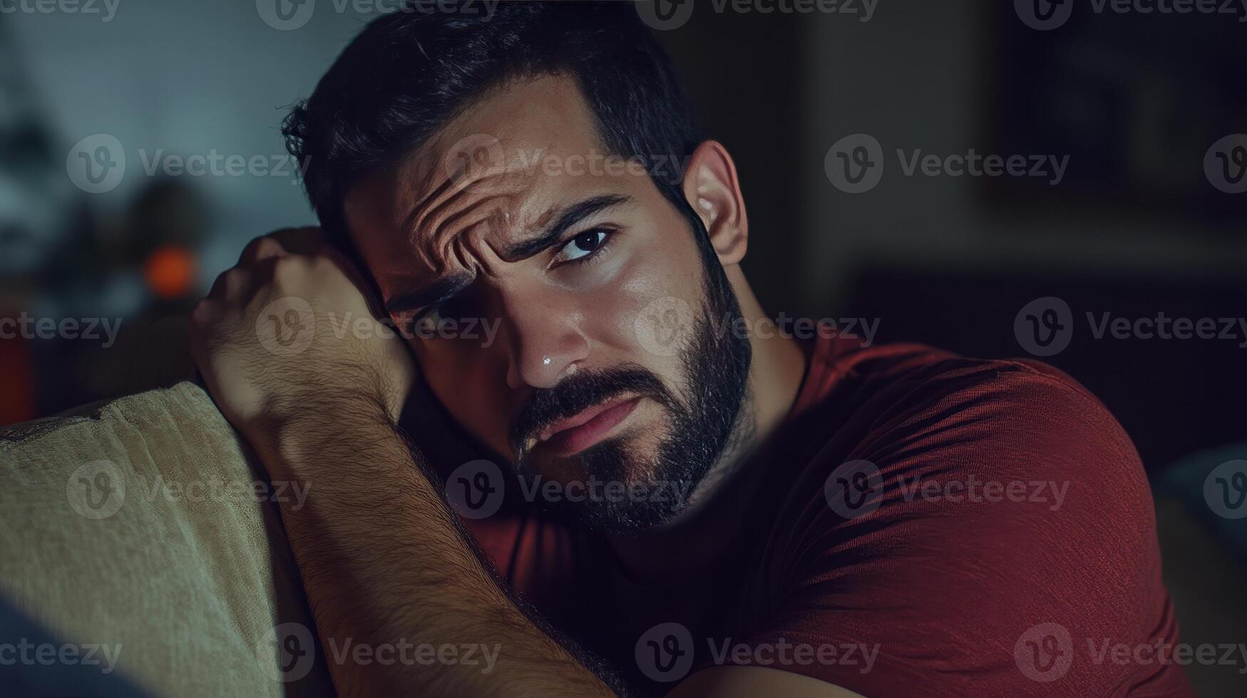 A man reflects quietly in a dimly lit room, lost in thought and emotion photo