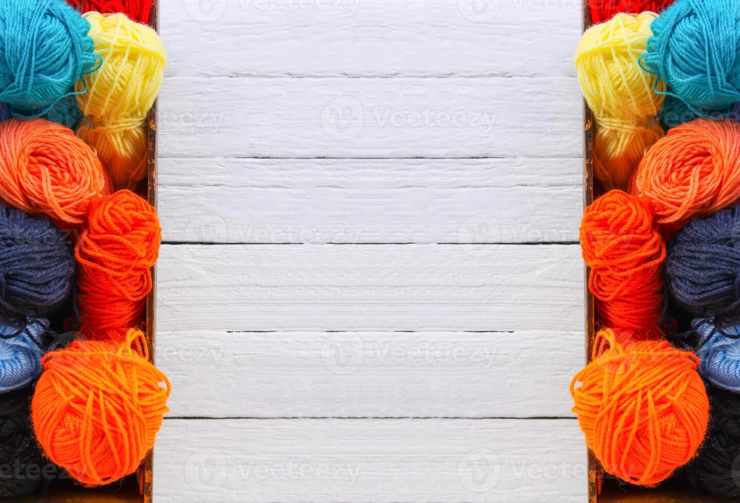 Colorful yarn balls in wooden box on white wood boards background. photo