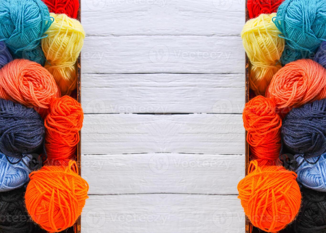 Colorful yarn balls in wooden box on white wood boards background. photo