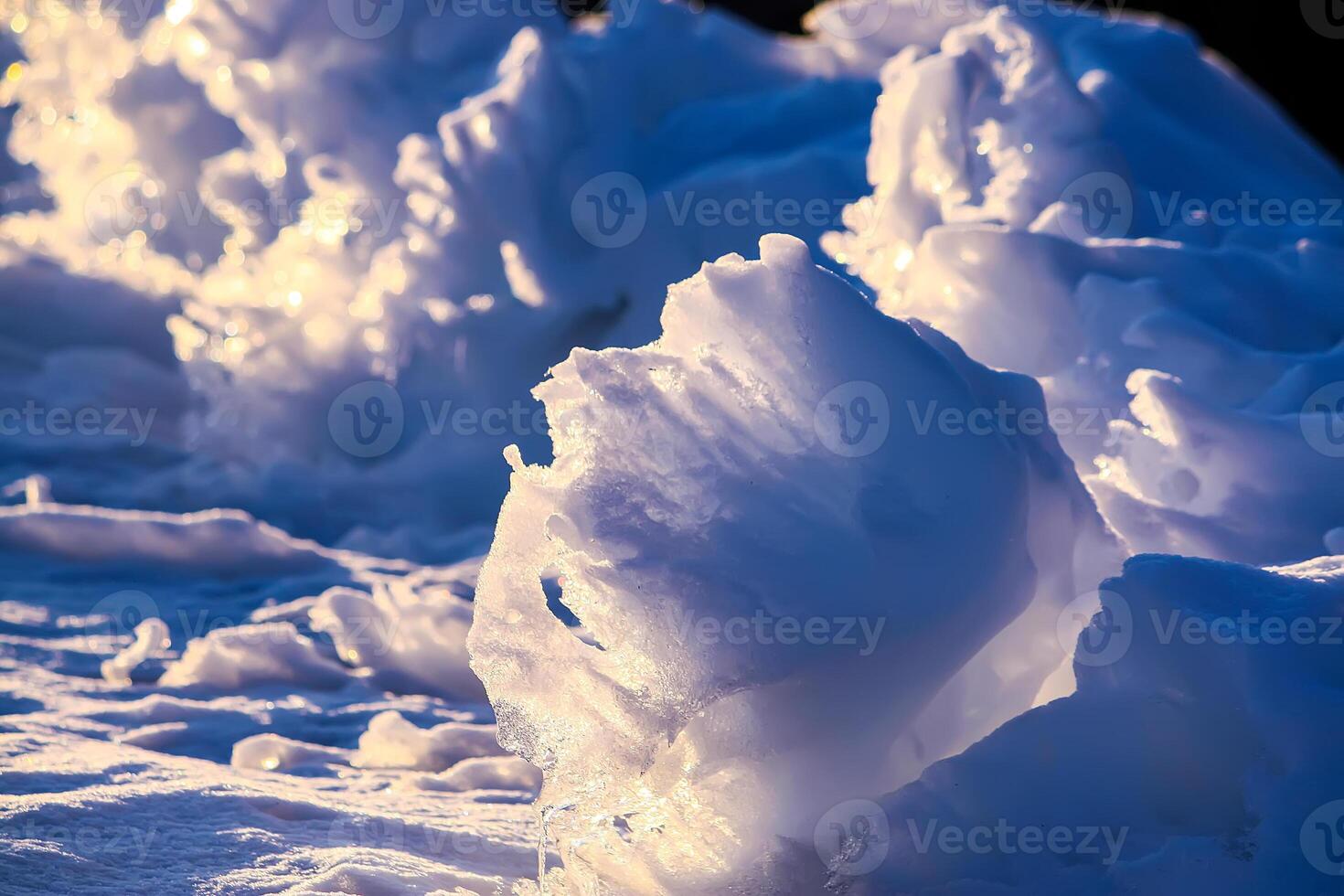 Melting snow and ice surface close up in evening sunlight in wintertime photo
