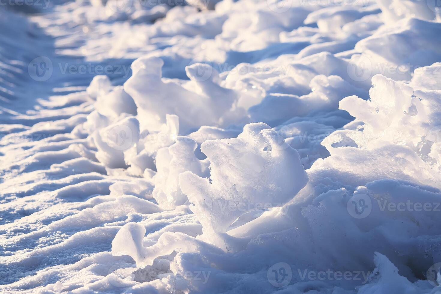 Melting snow and ice surface close up in evening sunlight in wintertime photo