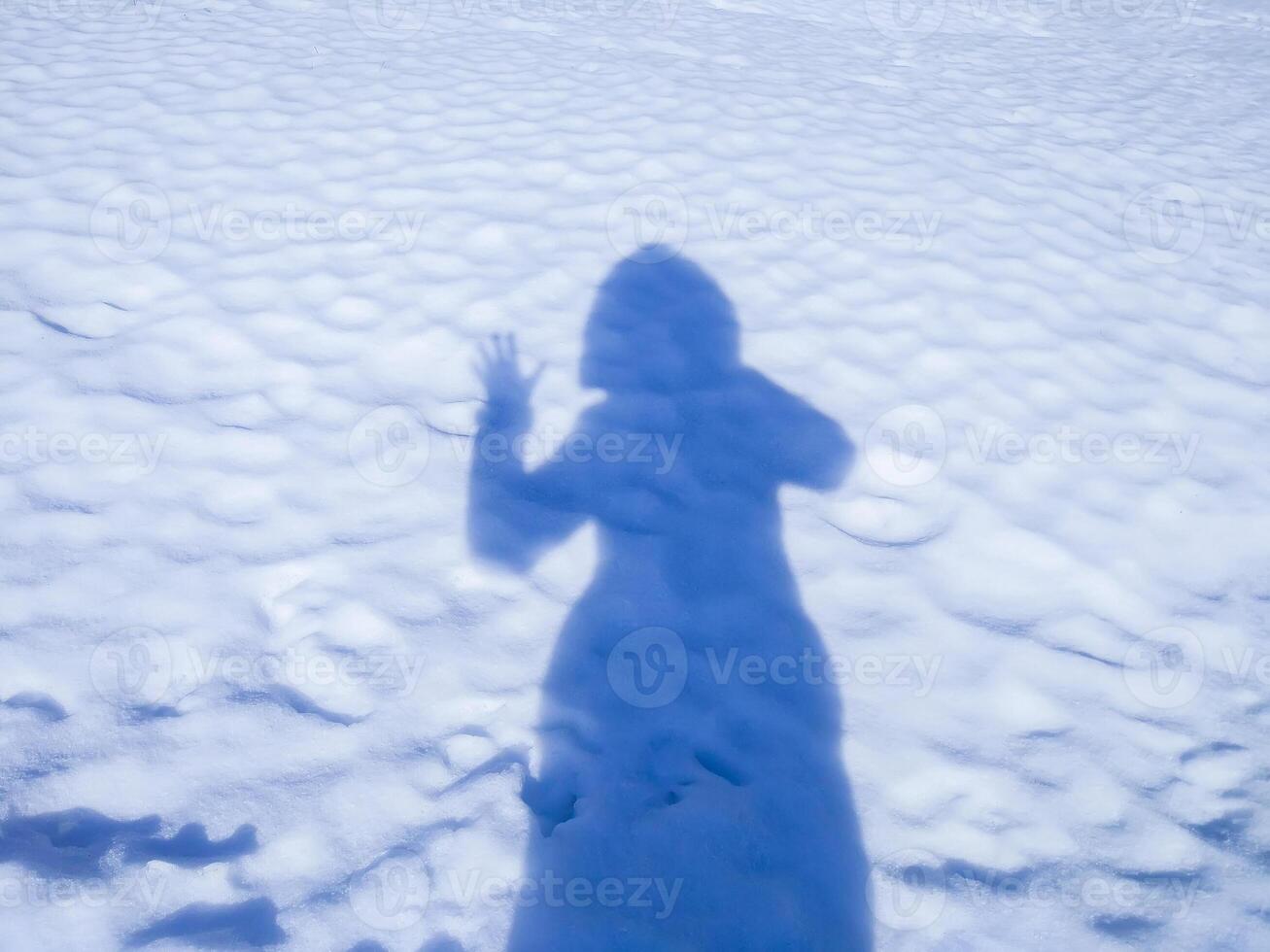 Female shadow waving her hand and making welcome gesture on snow surface in sunny day. photo