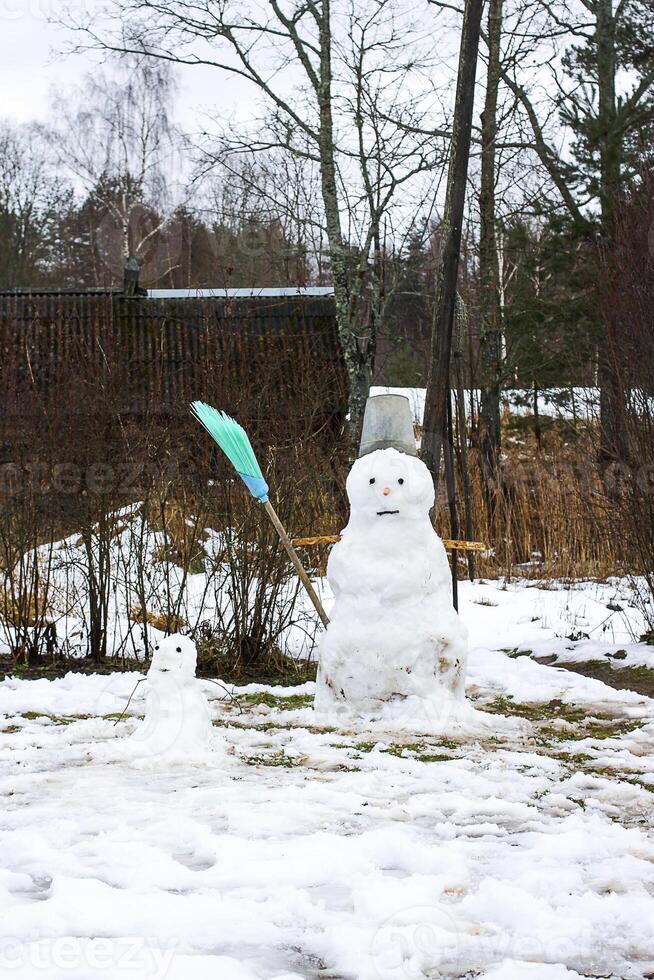 Cute snowman on rural yard. photo