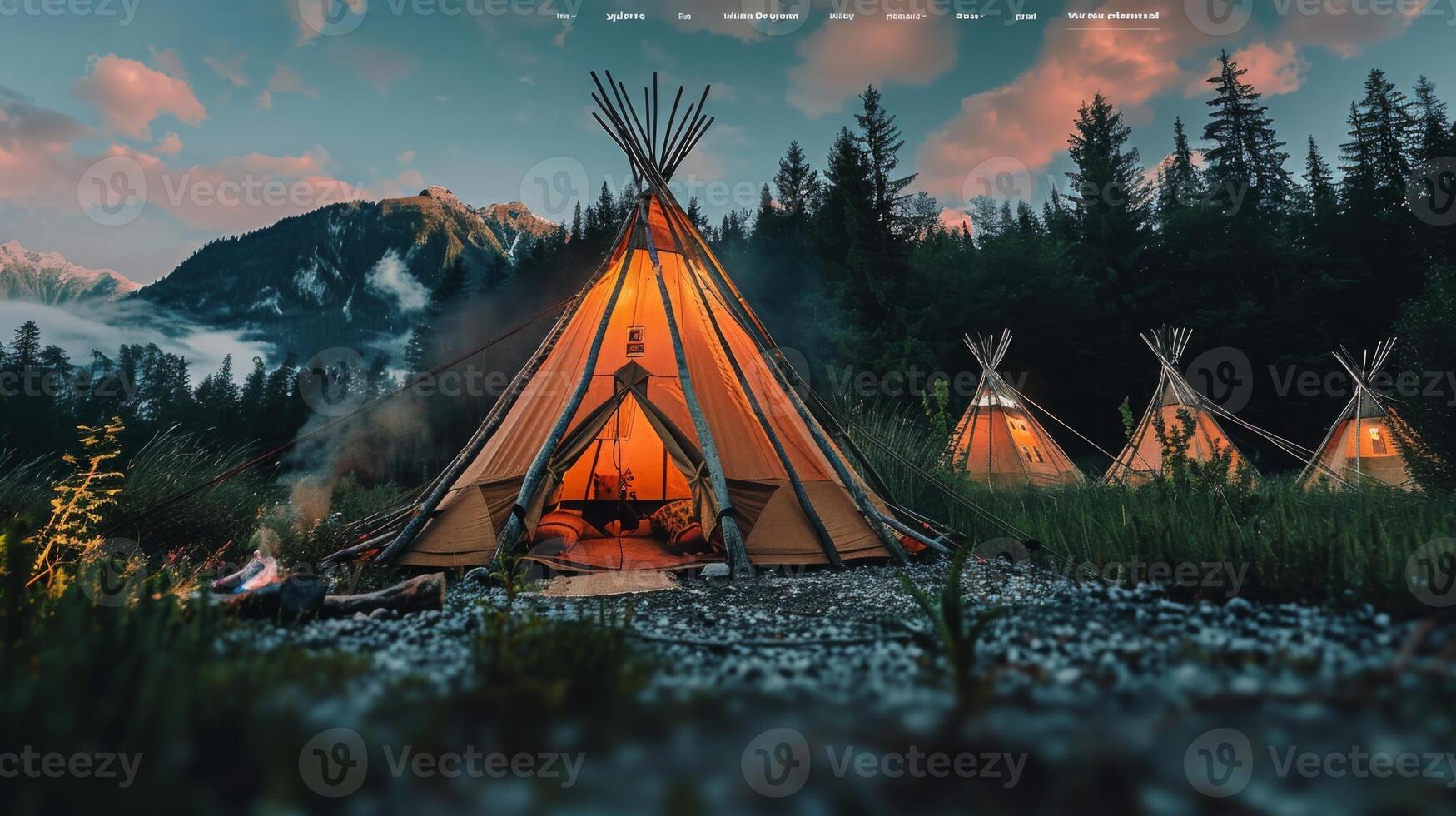 Teepees glowing in the twilight at a campsite nestled among forests and mountains photo