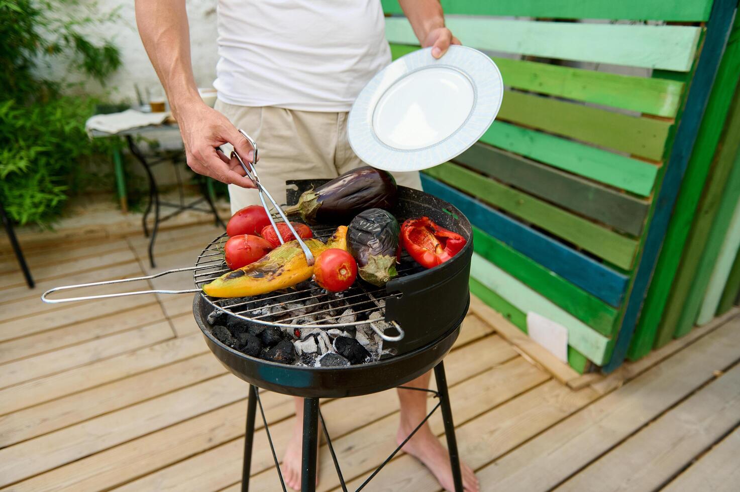 Man grilling vegetables on a backyard BBQ grill, preparing a healthy and delicious outdoor meal photo