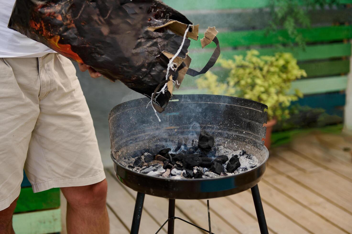 Outdoor barbecue preparation with person adding charcoal to the grill photo