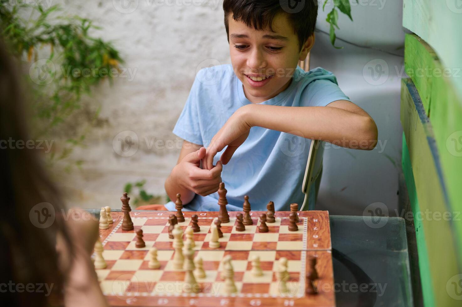 Smiling boy playing chess outdoors with a friend on a sunny day photo
