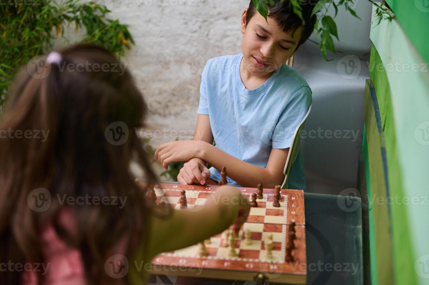 Children playing chess outdoors, enjoying a strategic board game in a garden setting photo