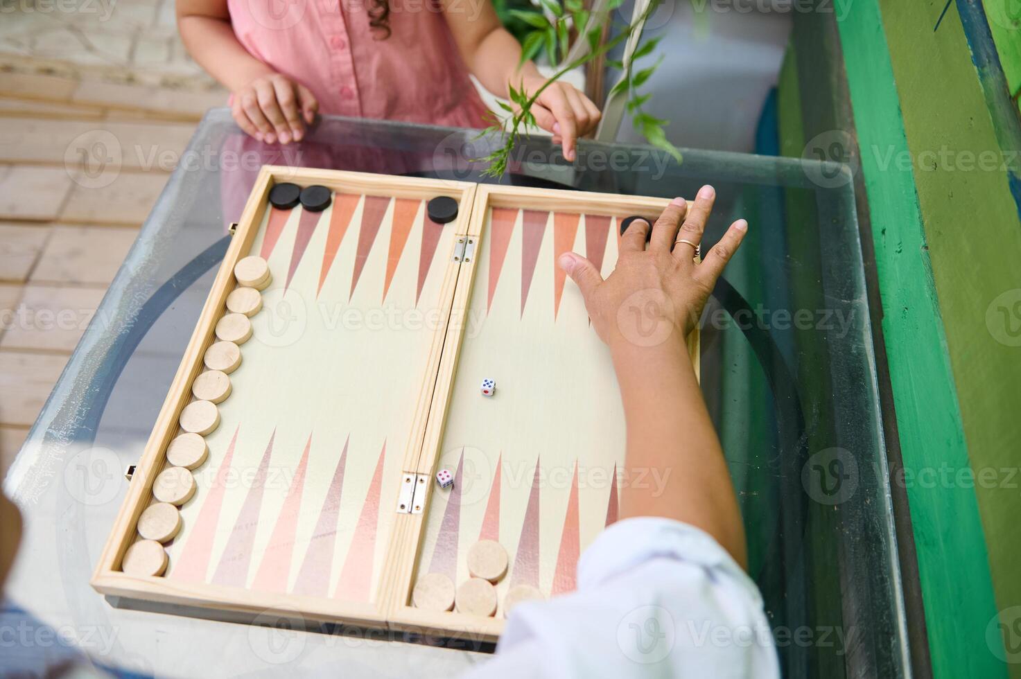 Two people playing backgammon on a glass table during a relaxing day photo