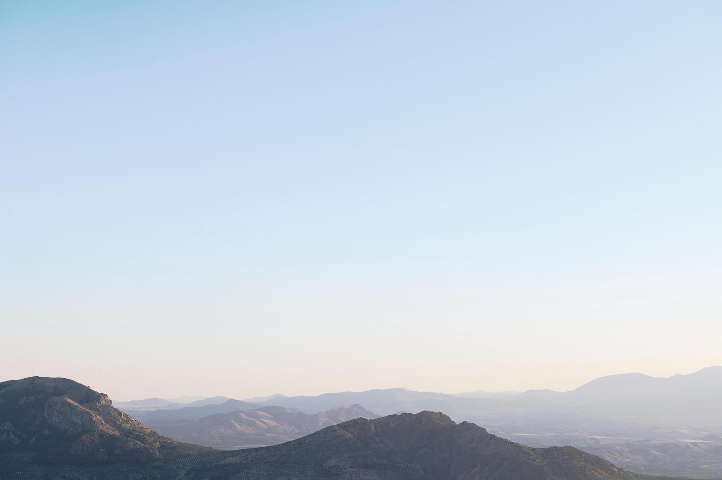 Serene mountain landscape during sunrise with clear blue sky and gentle slopes photo