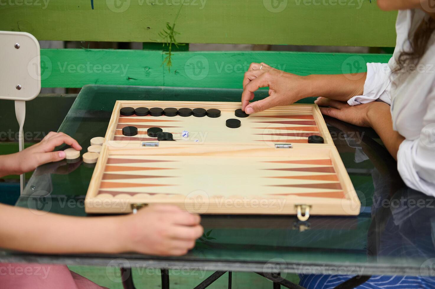 Hands playing backgammon on a wooden board in a relaxed outdoor setting photo
