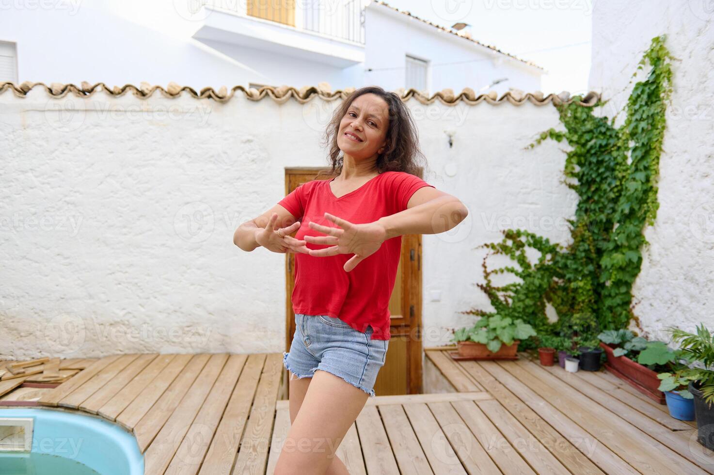 Woman enjoying outdoor relaxation in sunny courtyard with plants and wooden deck photo
