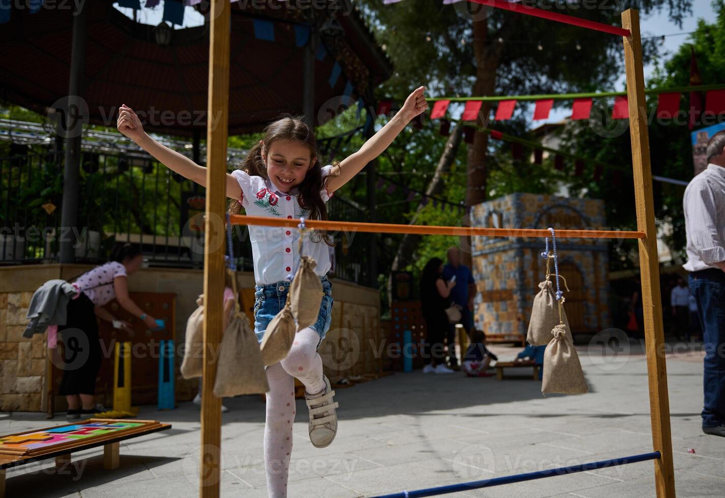 Young girl enjoying outdoor festival game with burlap sack obstacles on a sunny day photo