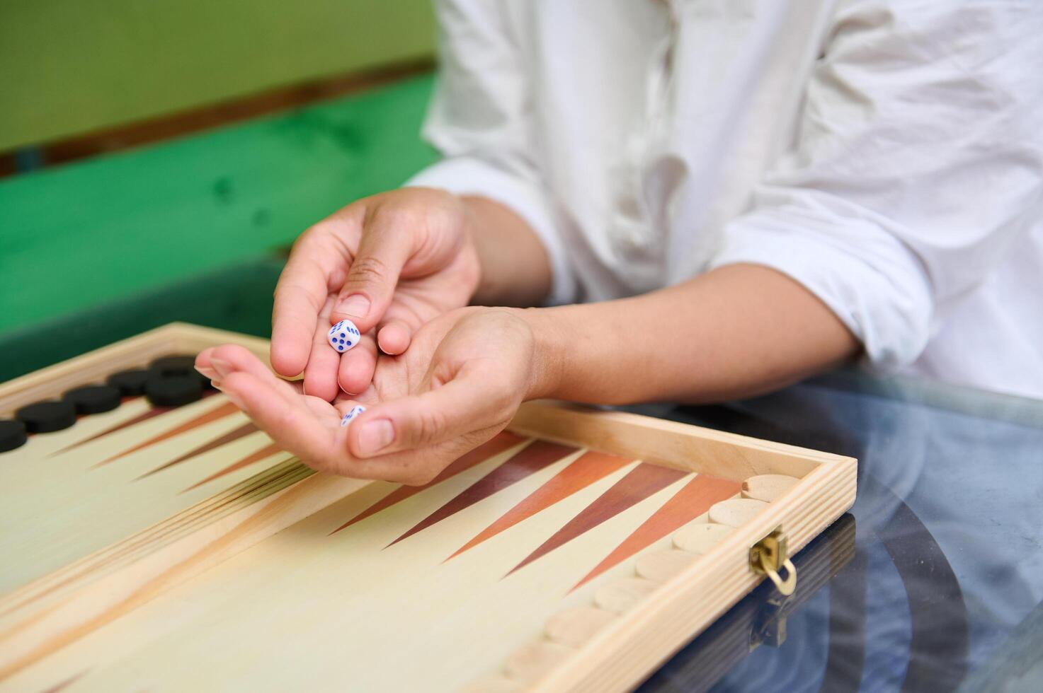 Hands holding dice while playing backgammon on a wooden board photo