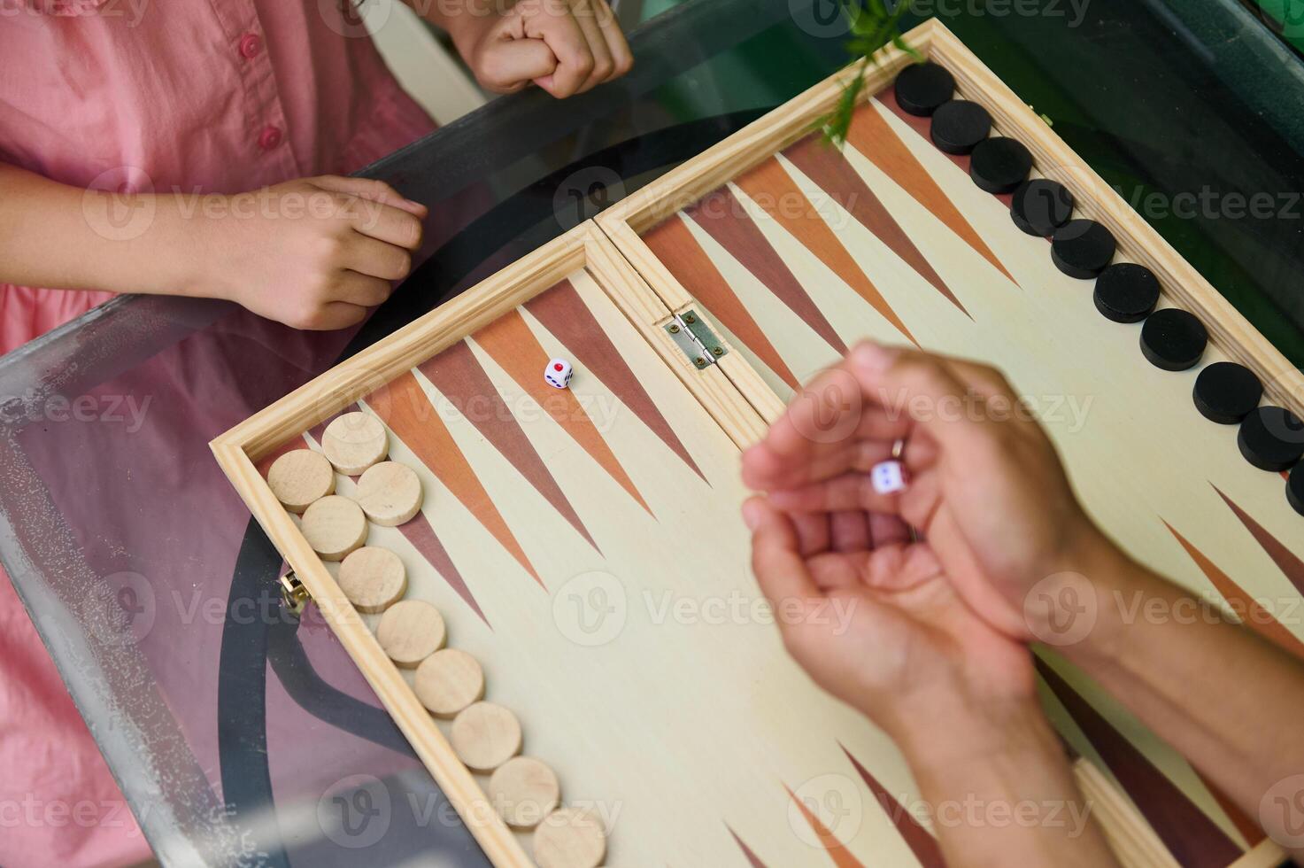 Children playing backgammon on a glass table, enjoying a classic board game photo
