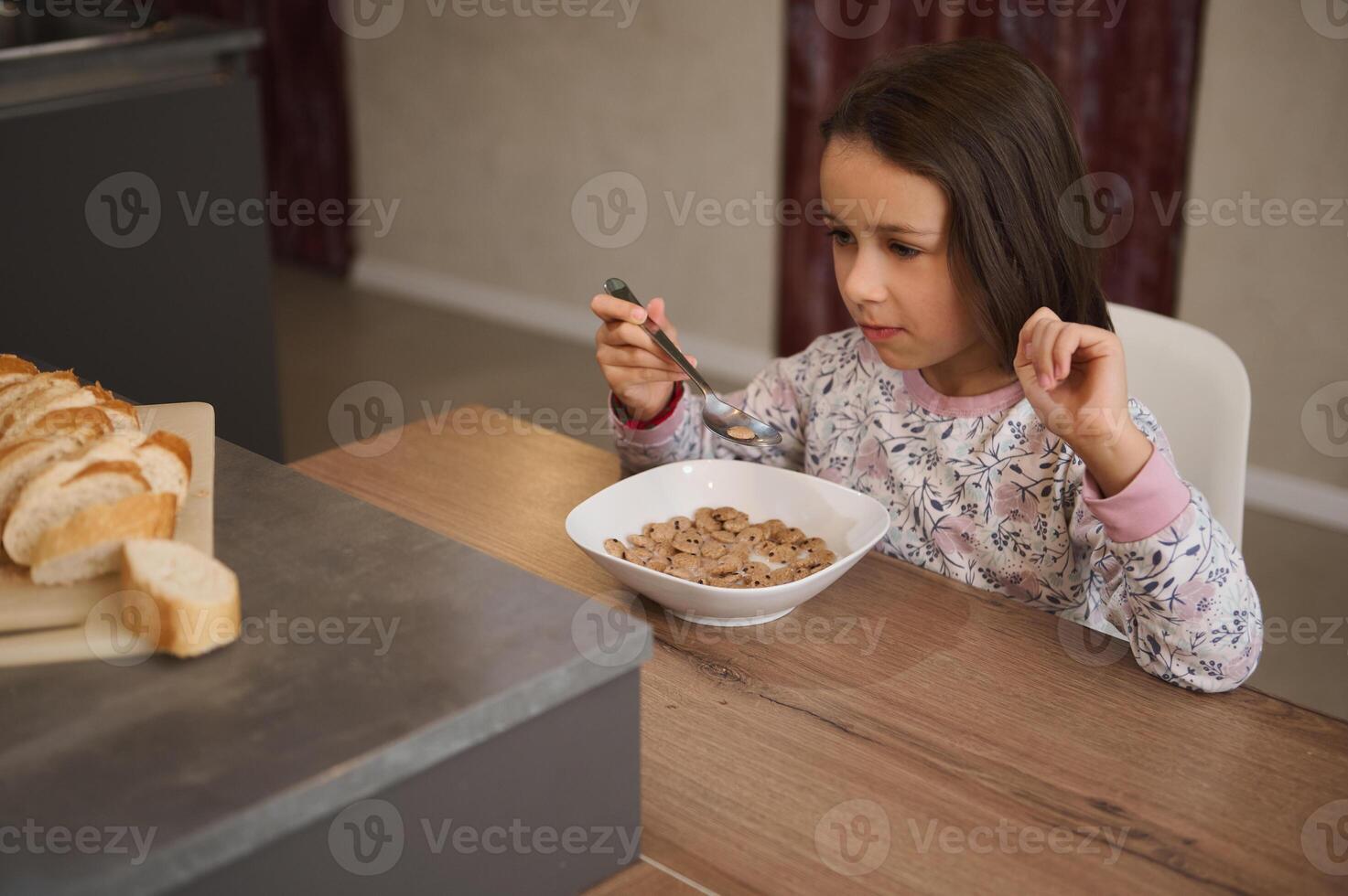 Young girl eating breakfast cereal at home, enjoying a morning meal photo