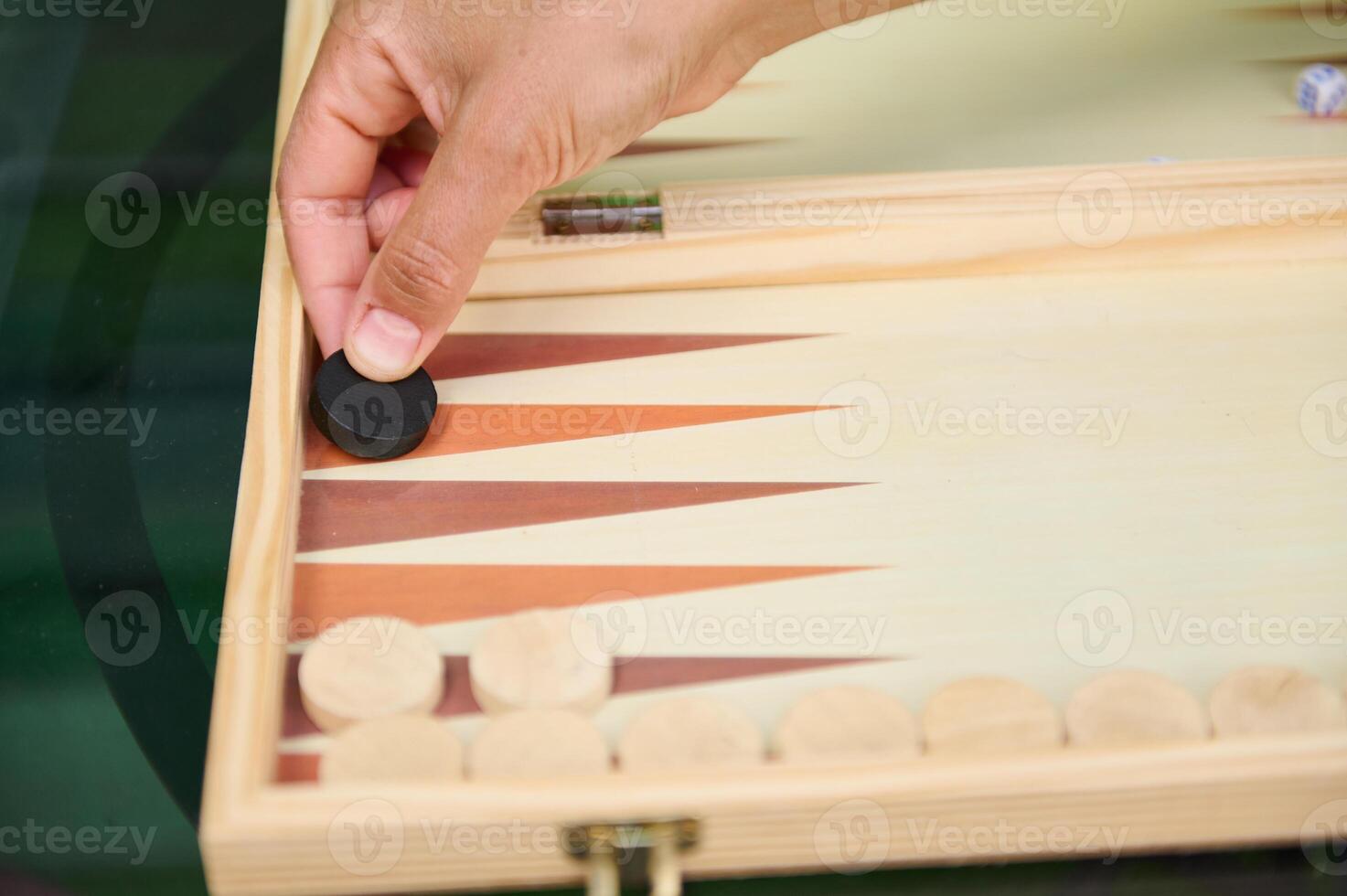 Hand placing chip in backgammon game on wooden board photo