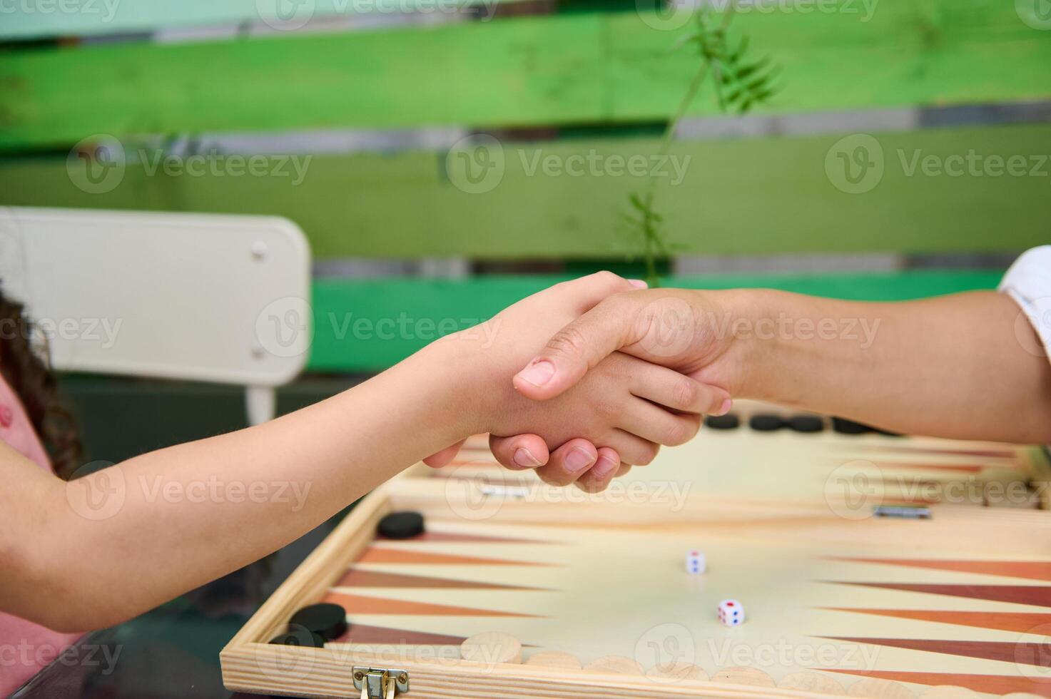 Two people shaking hands over a backgammon game, symbolizing agreement and sportsmanship photo