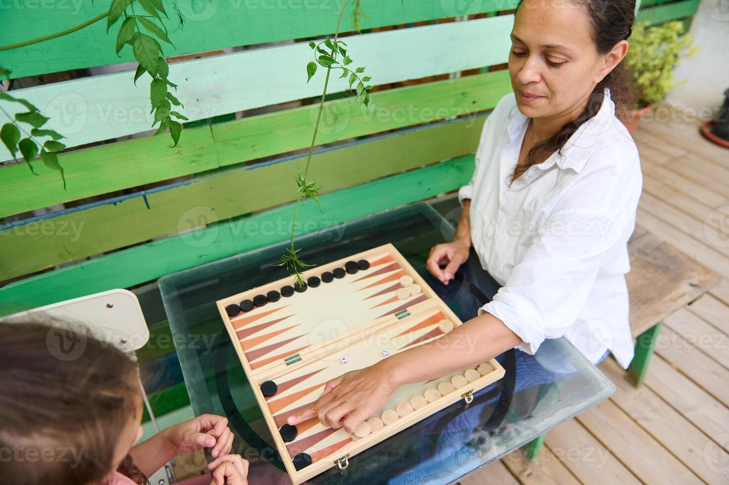 Mother and daughter playing backgammon outside on a sunny day photo
