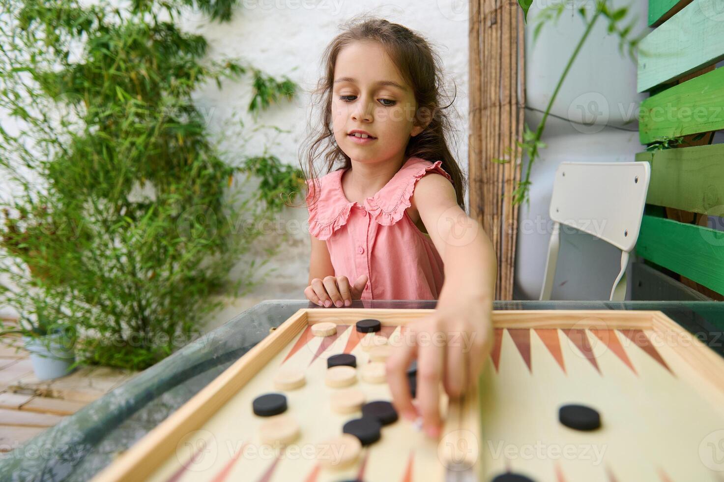 Young girl playing backgammon in a garden setting on a sunny day photo