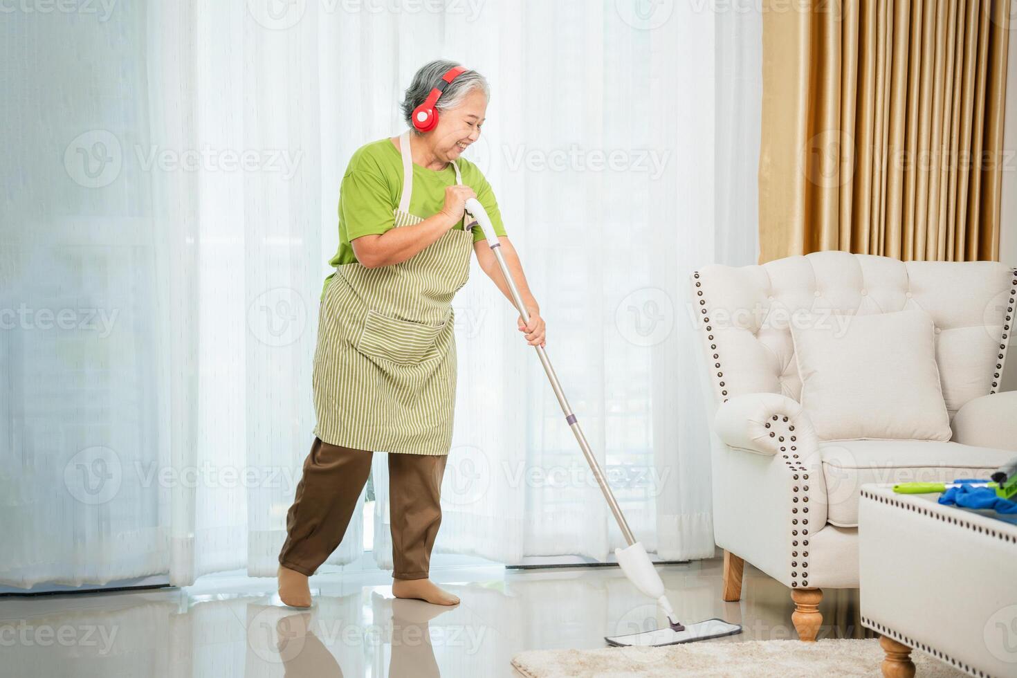 Cheerful senior woman housekeeping, Happy woman cleaning the house, Professional female housekeeper with cleaning tools photo
