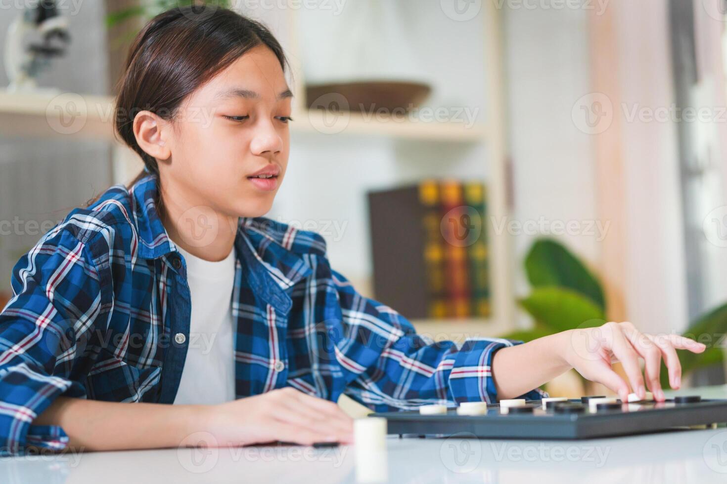 Asian teenage girl playing board game, Asian kid girl relaxing hobbies playing a game of checkers photo