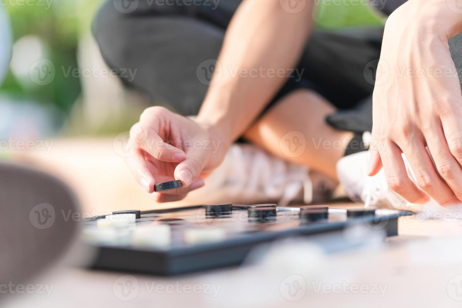 Close up of Asian teenage boy hand and girl playing board game, Asian brother and sister relaxing hobbies playing a game of checkers outdoor photo