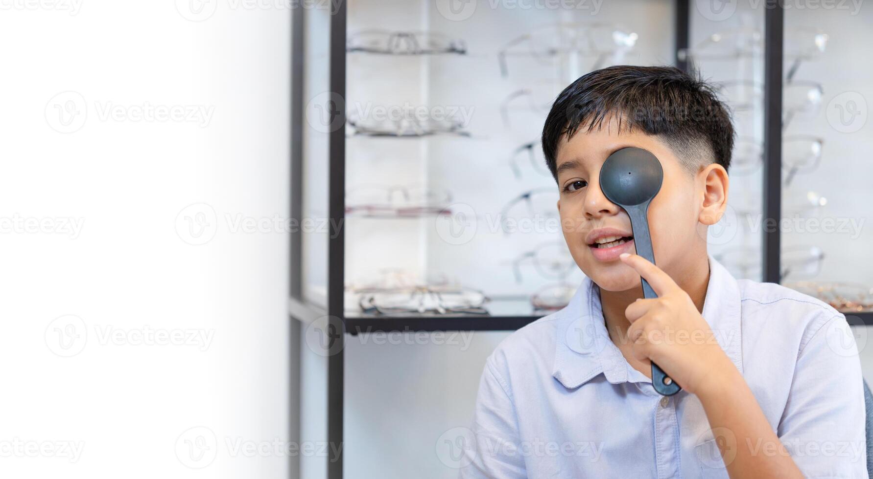 Indian kid boy choosing eyeglasses in optics store, Optometrist doing color blindness disease perception test in optical shop, Boy doing eye test checking examination with optometrist in optics store photo
