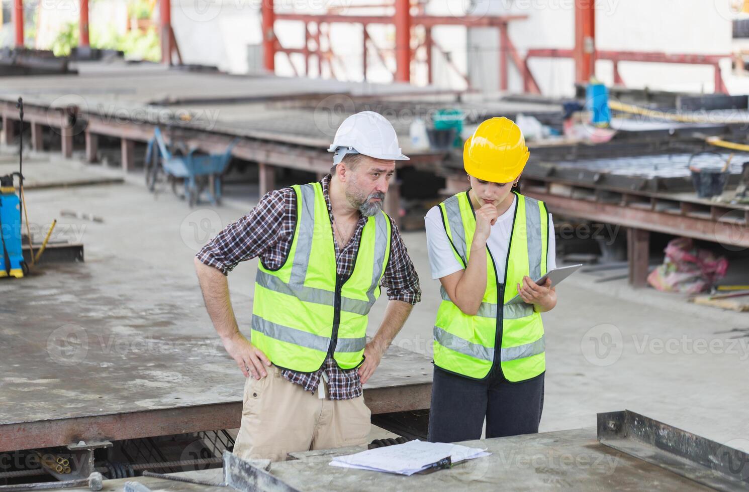 Caucasian engineer and female foreman worker with blueprints checking project at the precast concrete factory site, Engineer team in hardhats discussing on construction site photo